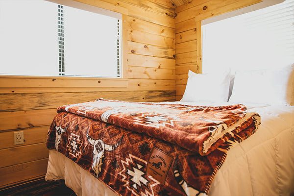 Bed with a patterned blanket in a wooden cabin room