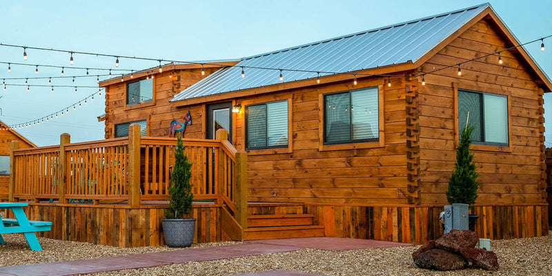 Wooden cabin with a deck and outdoor furniture under a clear sky.