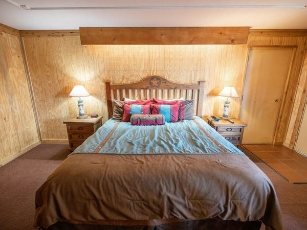 Bedroom with wooden walls and a bed with colorful pillows.