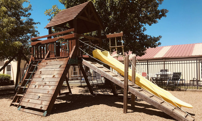 Wooden playground structure with a yellow slide in an outdoor setting