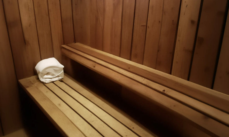 Wooden bench in a sauna with a white towel draped over it