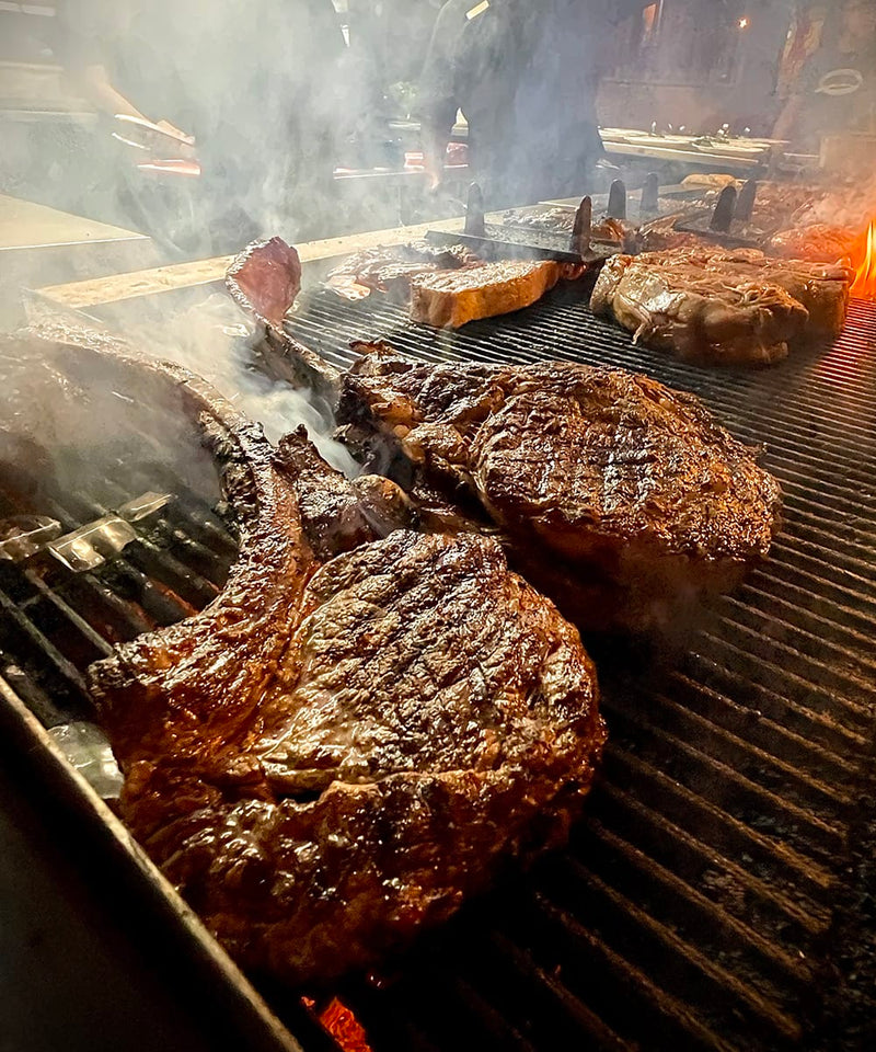 Steaks being grilled with smoke rising.