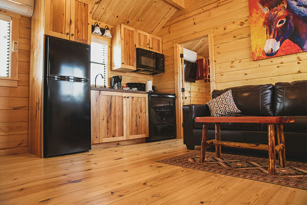 Wooden cabin interior with kitchen appliances and living area.