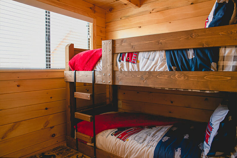 Bunk bed with colorful bedding in a wooden room