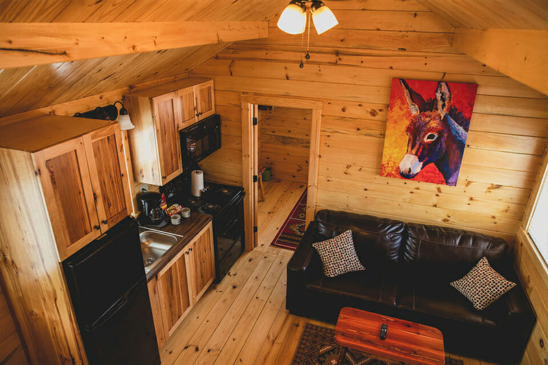 Small living area with wooden walls, a kitchenette, and a couch.