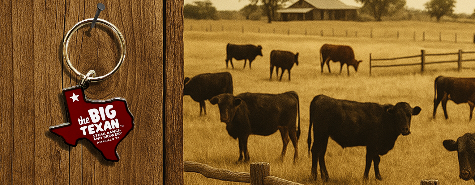 Keychain shaped like the state of Texas with 'The Big Texan' logo on a wooden surface, with a sepia-toned photo of cows in a field in the background.