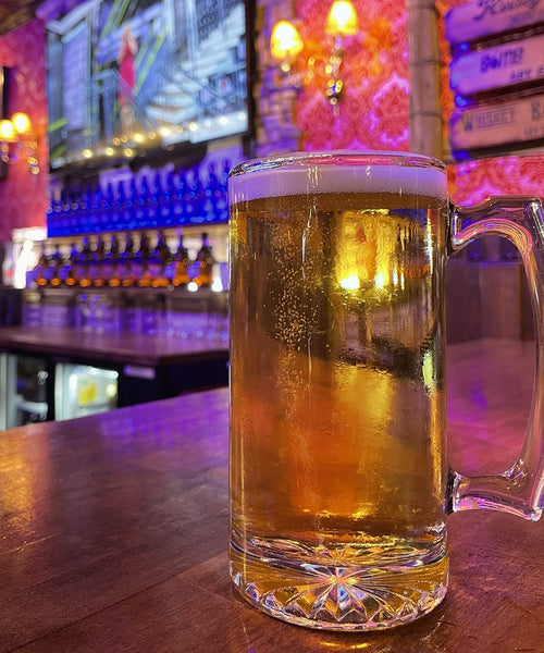 Glass of beer on a bar counter with a colorful bar background