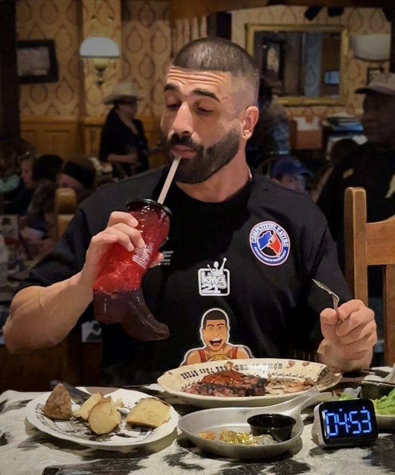 Man eating at a restaurant with a drink and food on the table.