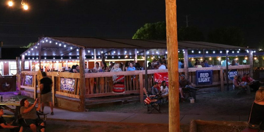 Outdoor deck with people sitting under string lights at night