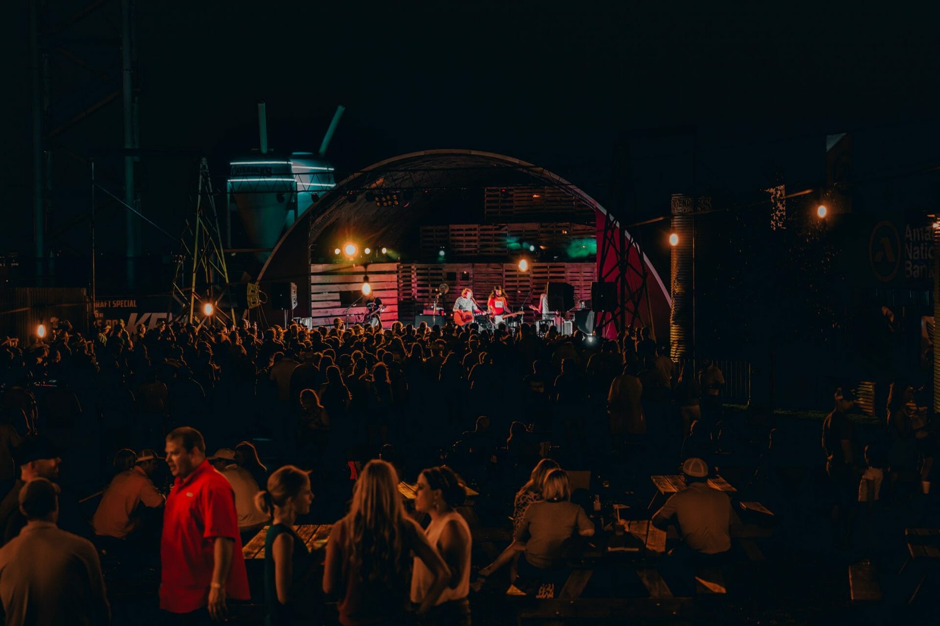 Live concert with band on stage at night, audience in foreground