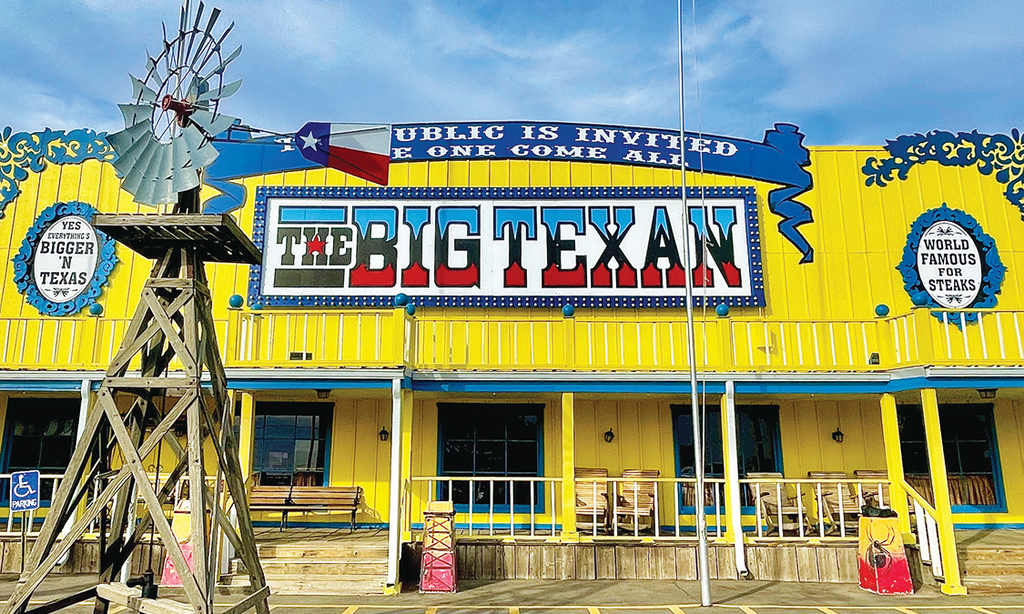 Front view of The Big Texan restaurant with a windmill and blue sky.